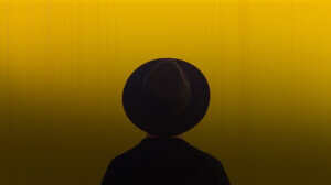 man wearing black hat against a Yellow wall