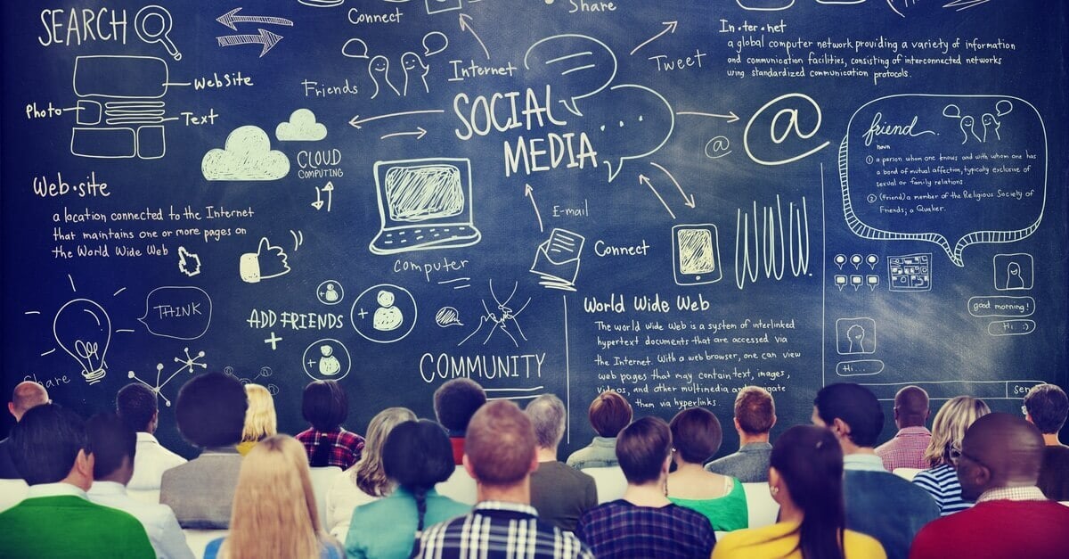 room full of adults looking at a black board with social media icons drawn on it