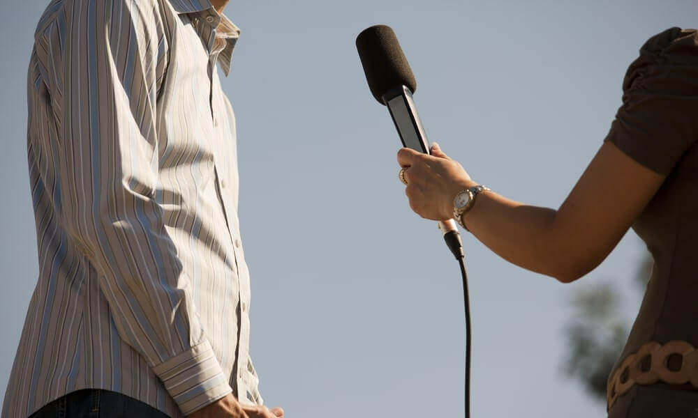 woman standing in front of reporter with microphone