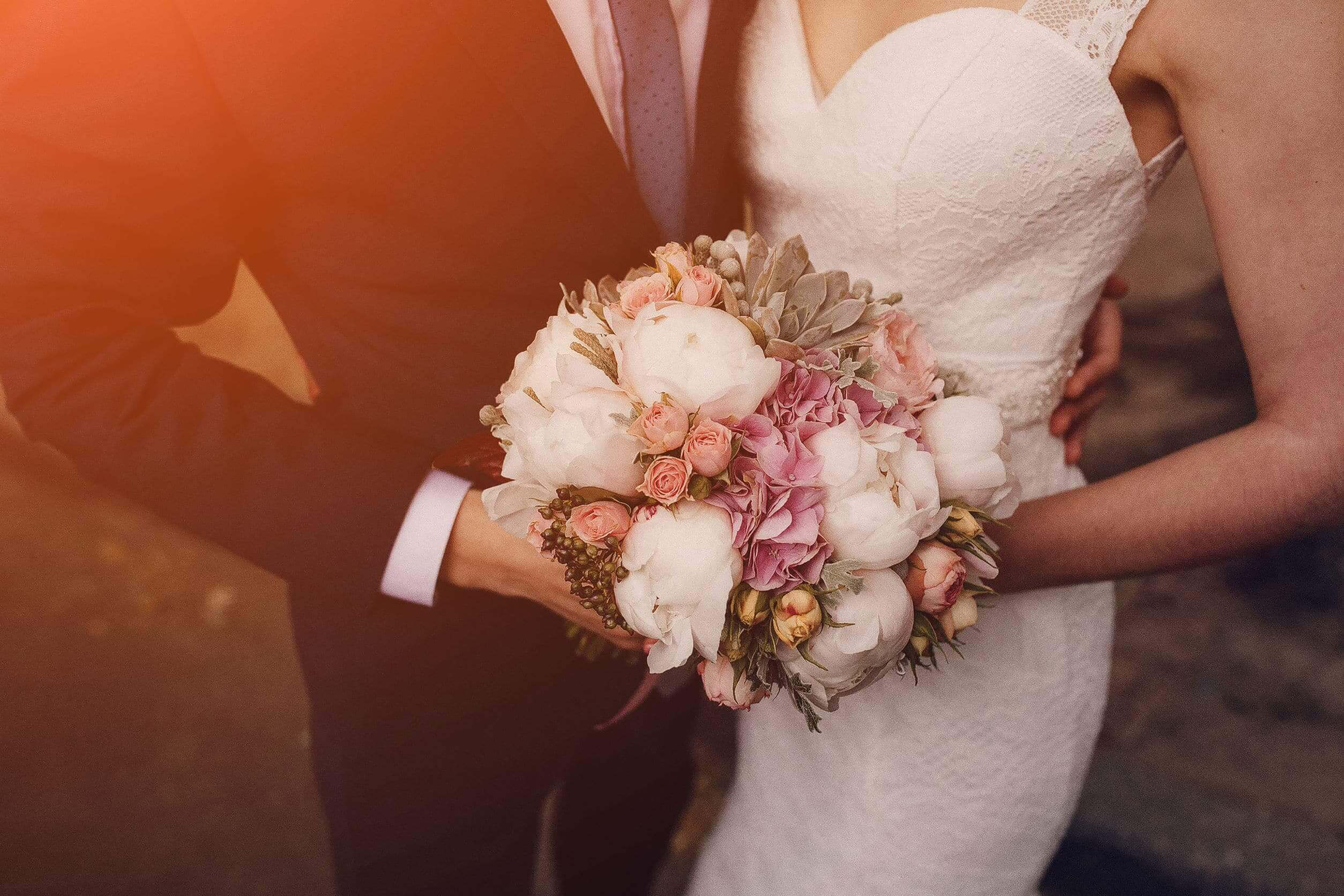 close up of bride and groom holding a bouquet of flowers